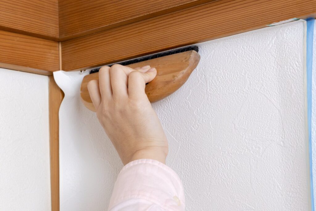 白い壁の仕上げを木のコテで押さえる職人の手元