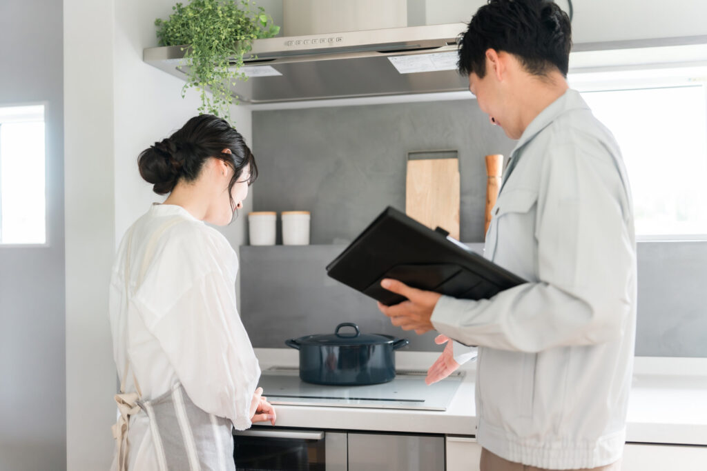 キッチンで、担当者が手帳を開いて住まいの困りごとを聞いているところ