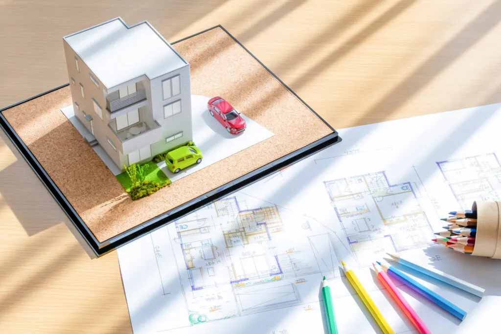 図面の上に置いた住宅模型と色鉛筆。プランを検討する打ち合わせ