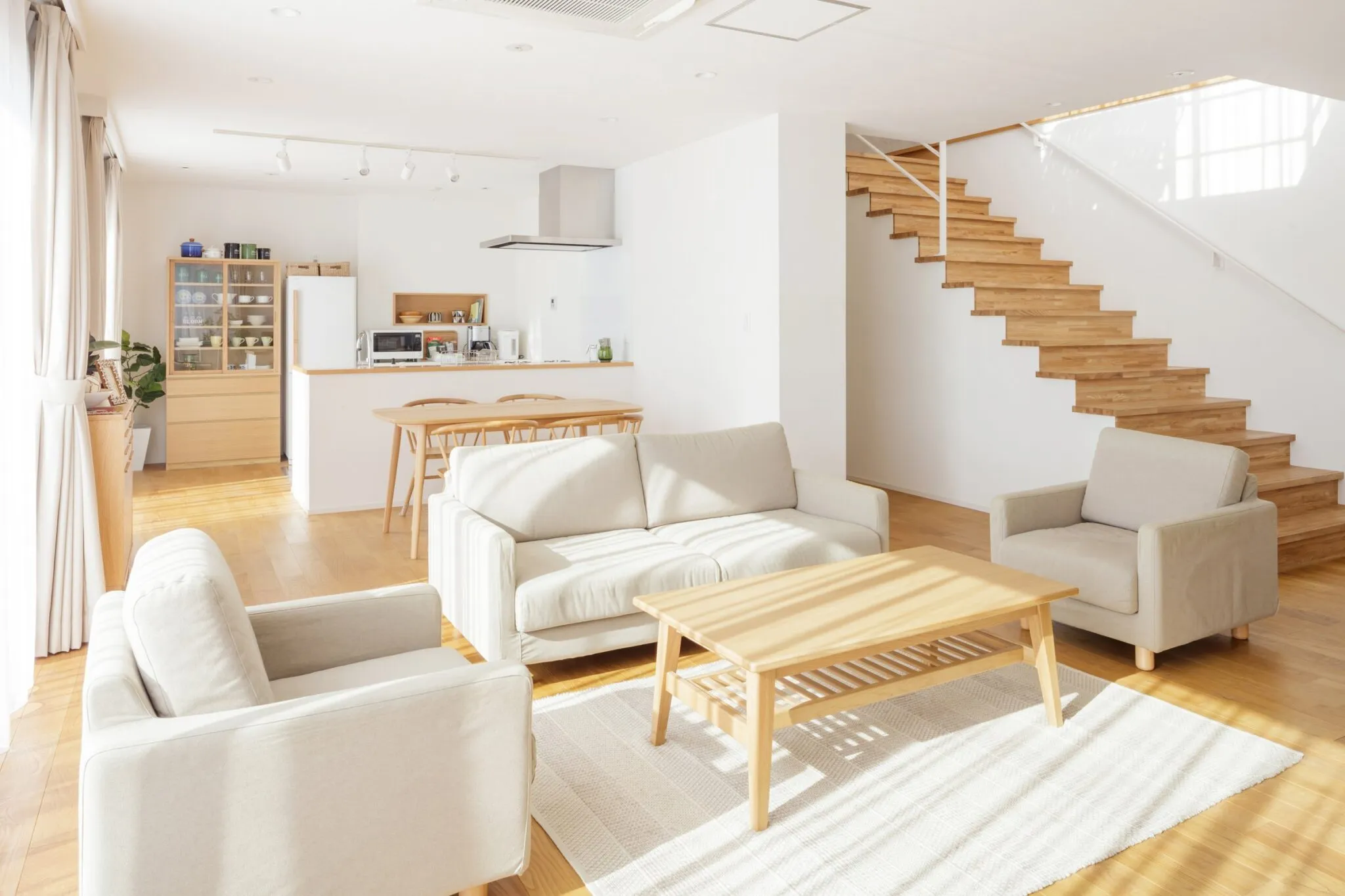白い壁と木の階段に光が入る、戸建てのリビング
